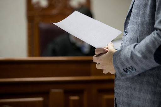 Person standing before a judge with piece of paper in hand