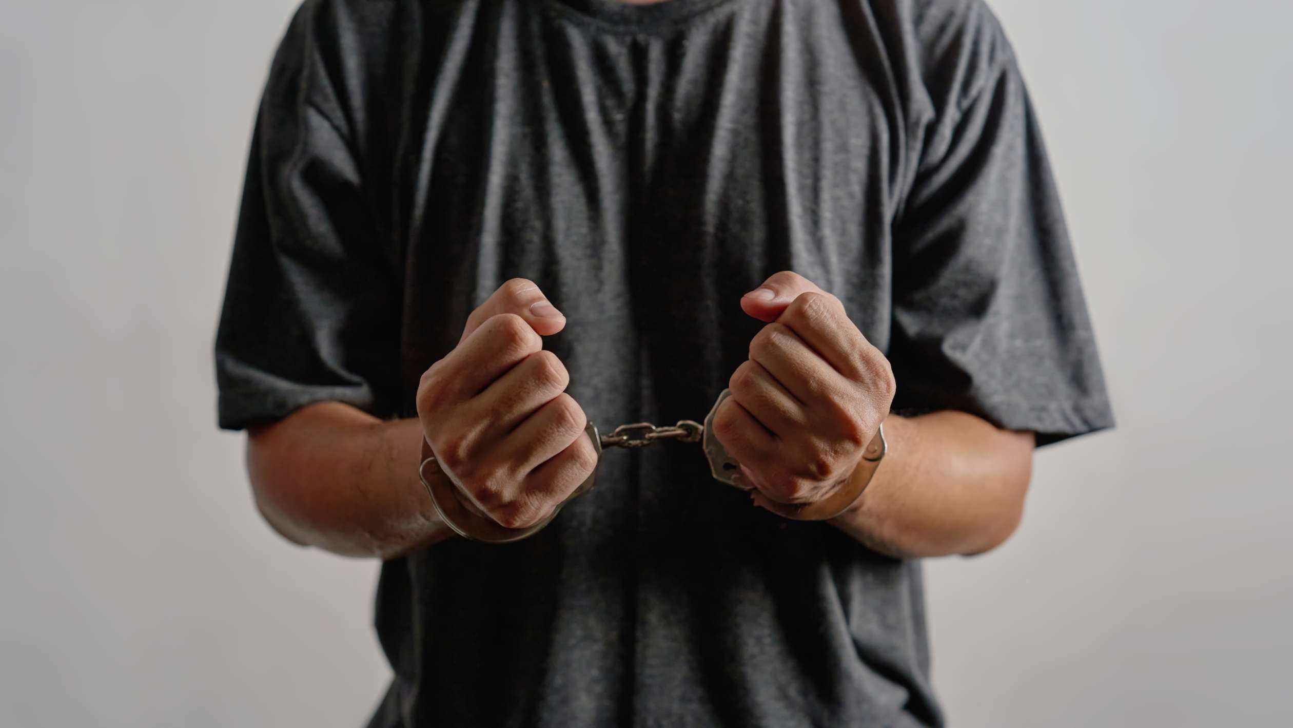 Man in a gray T shirt with handcuffs on