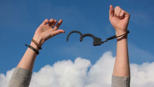 person with their hands in the air breaking free from handcuffs