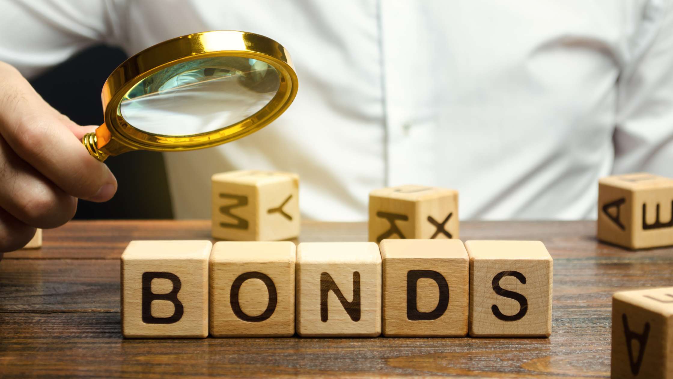 Man looking into a magnifying glass at blocks that spell Bonds