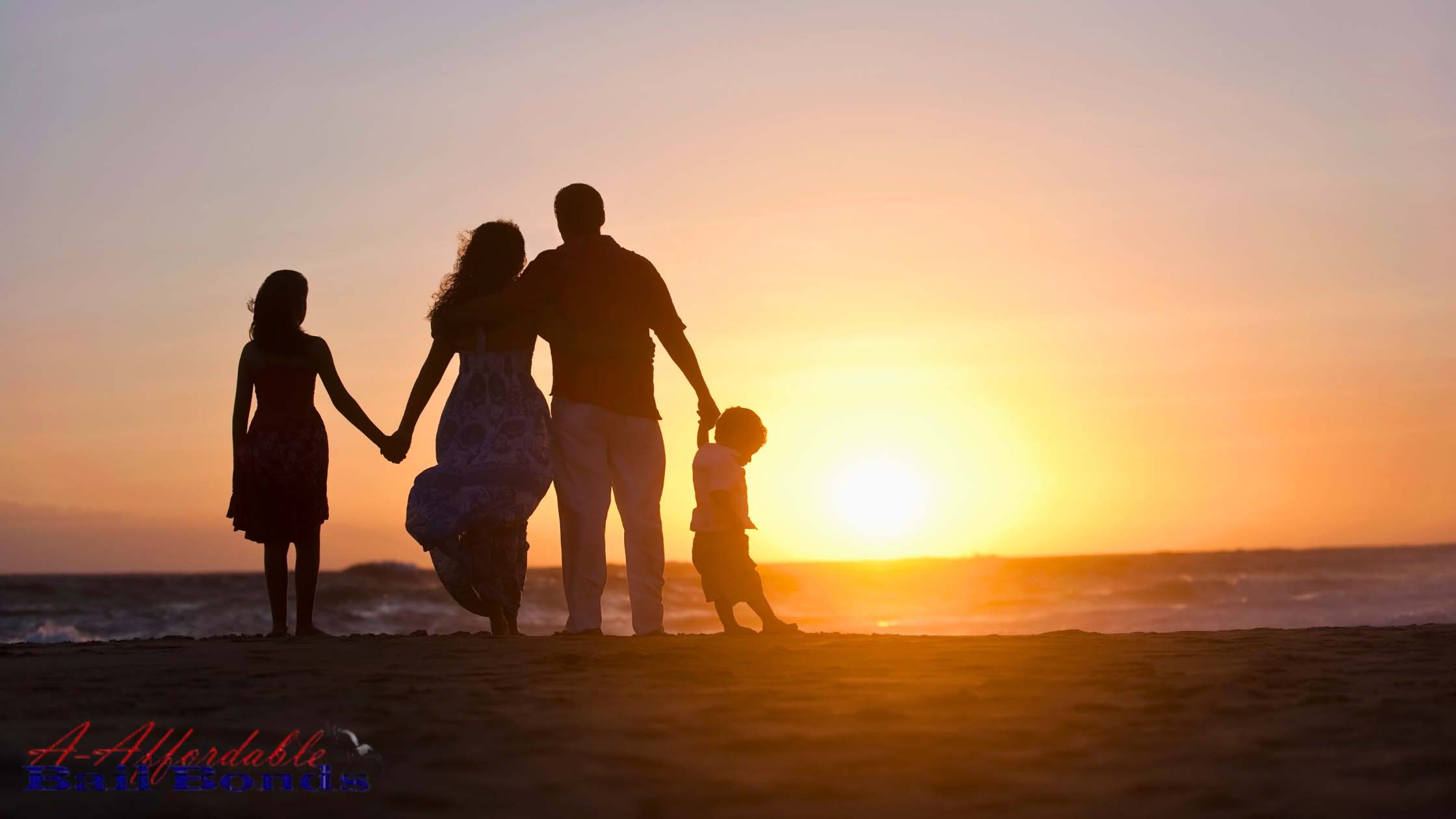 Family holding hands on the beach at sunset